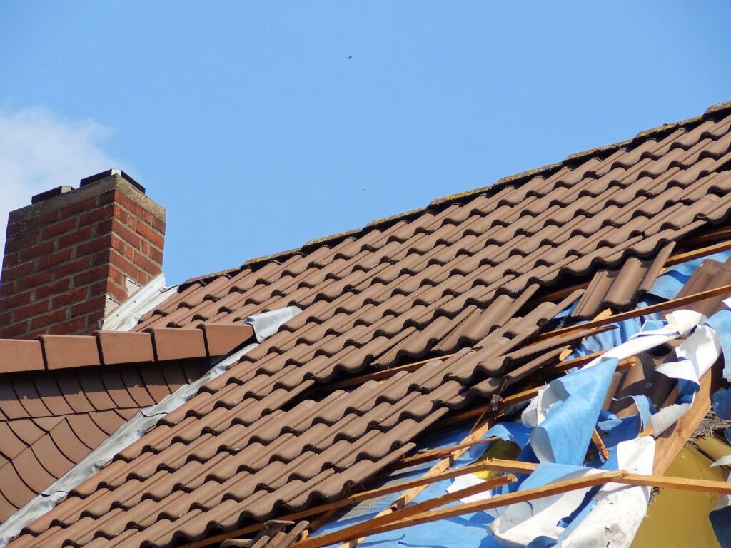 Damaged roof with missing tiles and tarp.